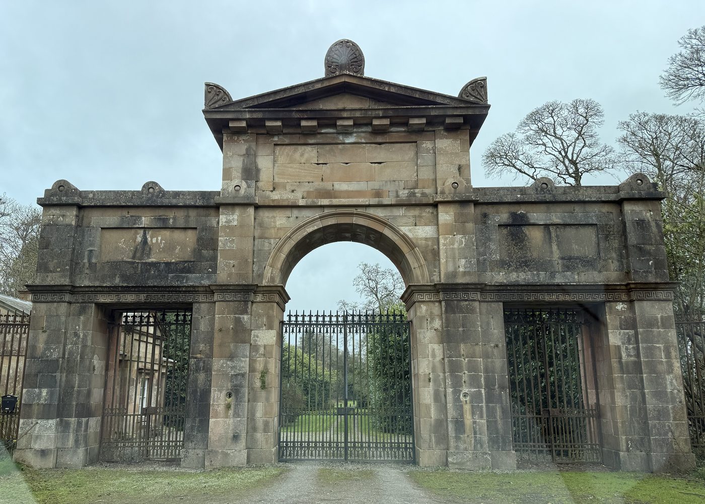 The grand Greek-Revival sandstone entrance gate to the Seaforde demesne, its central carriage arch and iron gates opening onto the drive.