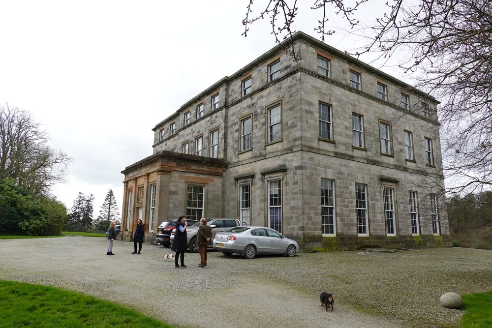 The group gathered in front of the house, cars parked on the gravel.