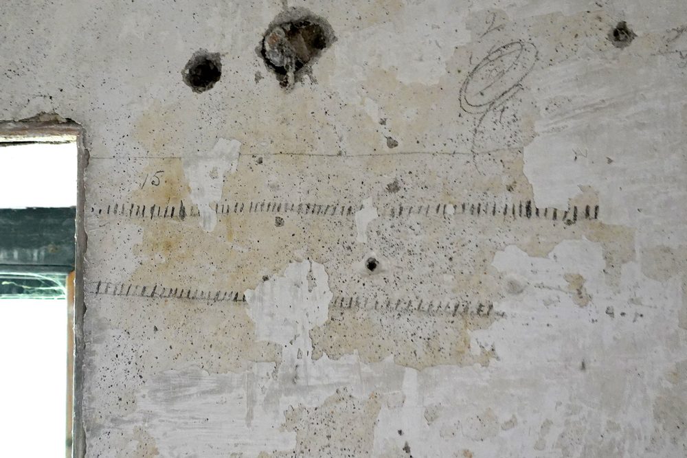 Tally marks and pencil notes scratched into an old plaster wall.