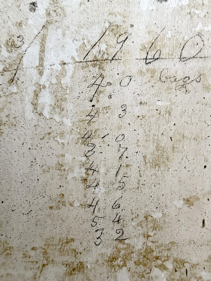 A handwritten inventory list in pencil, still visible on the wall.
