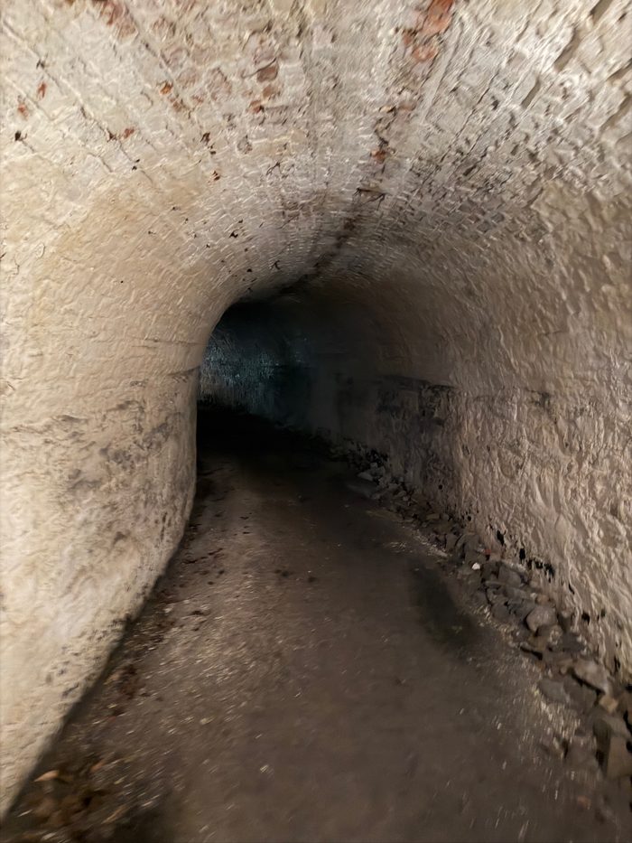 An empty brick-vaulted corridor, a single light glowing at the far end.