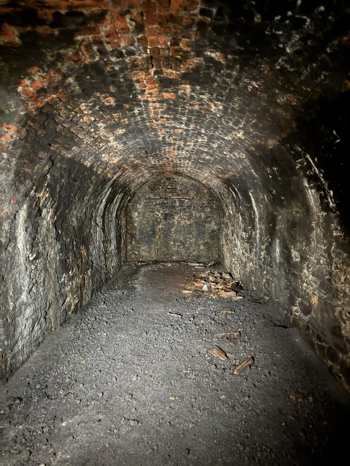 Another empty brick-vaulted corridor, receding into darkness.